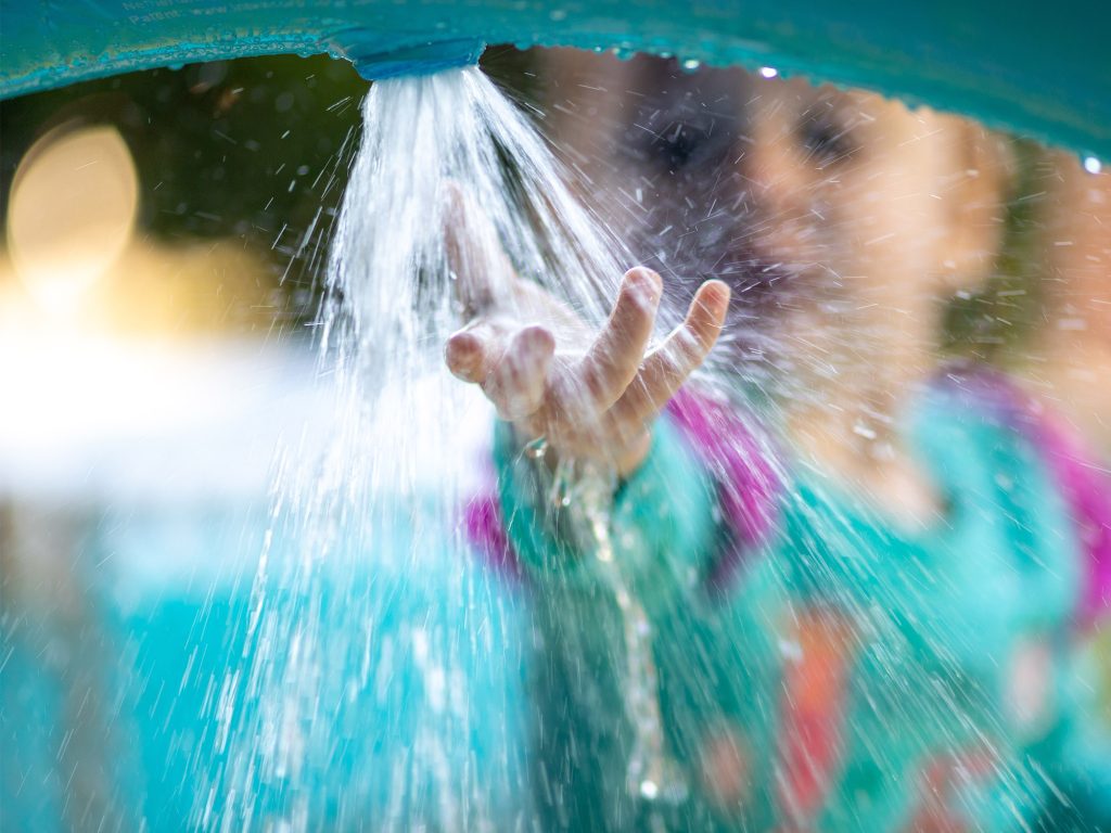 Child holding hand under water flow