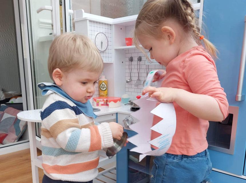 children in play kitchen with paper crown